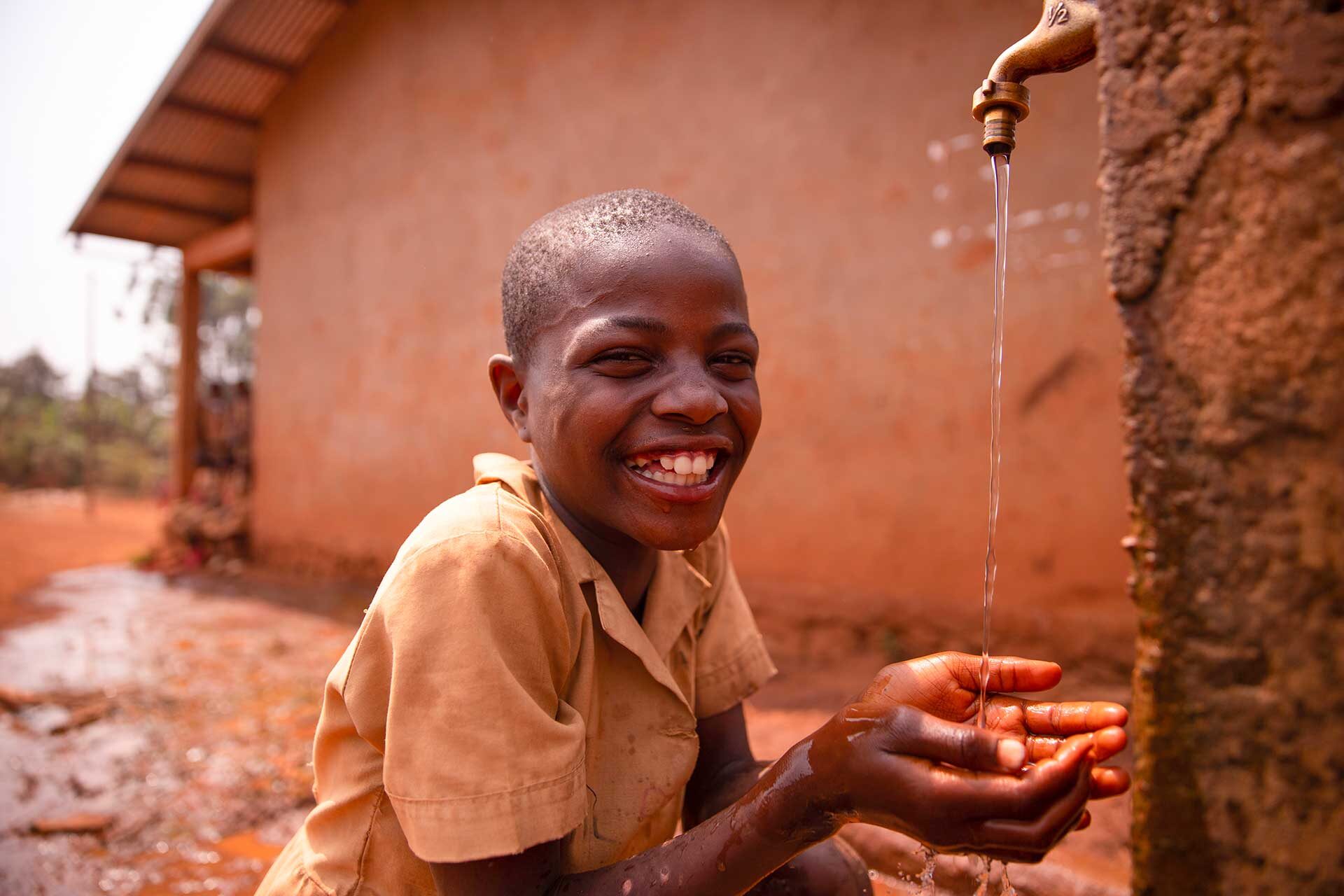 smiling-black-african-schoolboy-drinking-from-a-ta-2023-11-27-04-55-06-utc